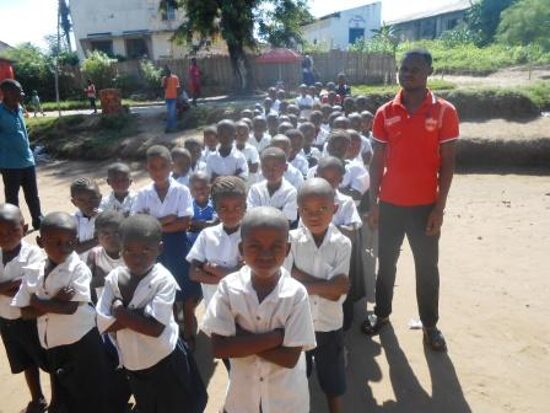 Pupils lined up in the schoolyard with a teacher