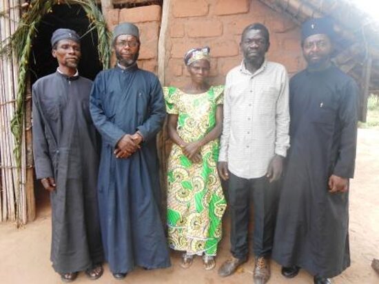 Three priests with two of the school staff in front of a building
