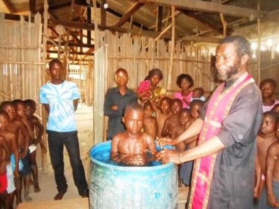 A priest in an epitrachelion baptizing a child by immersion in a barrel font