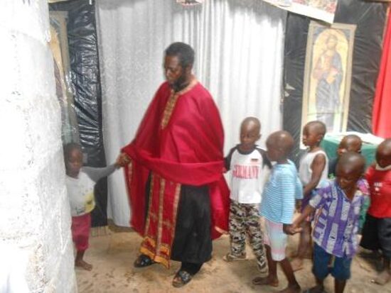 A priest in red vestments with children in the church