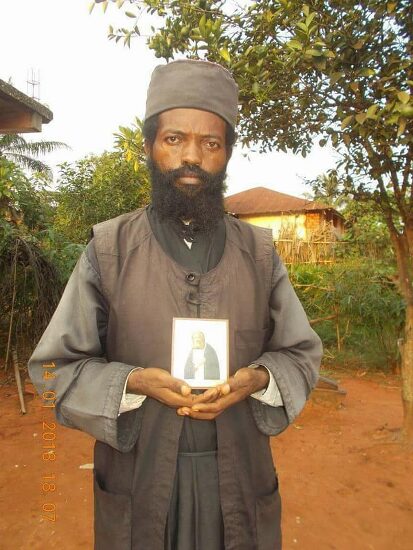 Father Theophile holding an icon, outdoors