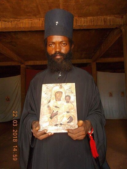 Father Theophile holding an icon of the Mother of God in the church