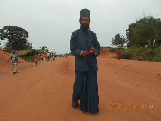 Father Theophile standing on a red dirt road
