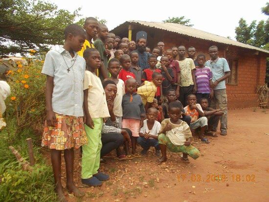 A large group of young people and children of the parish outdoors, Father Theophile among them