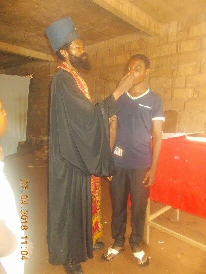 Father Theophile anointing a young man before his baptism
