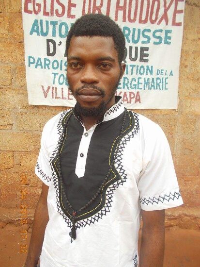 A young man of the parish in front of the church sign