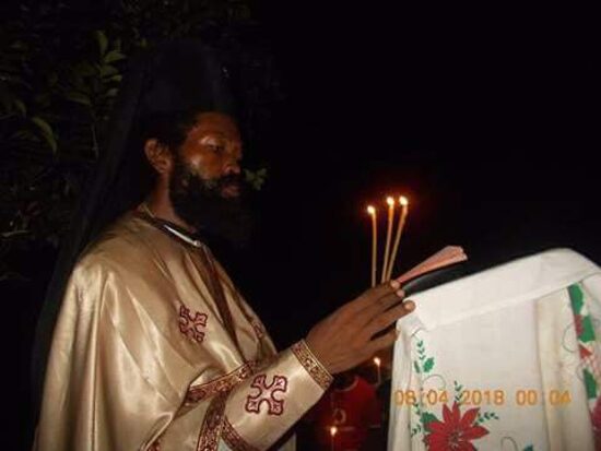 Father Theophile in vestments holding Paschal candles by night