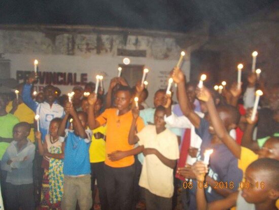The faithful holding lit candles outside at night