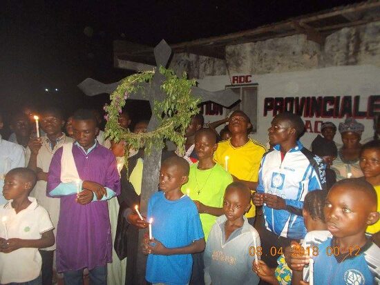 The faithful with candles around the cross hung with green branches