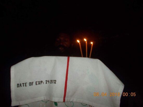 Father Theophile reading by candlelight at a lectern outside, the start of the Paschal service