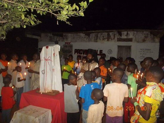 The faithful with candles around a table with an embroidered cloth, by night