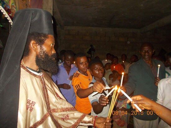 Father Theophile giving the Paschal light to the faithful, who light their candles from his